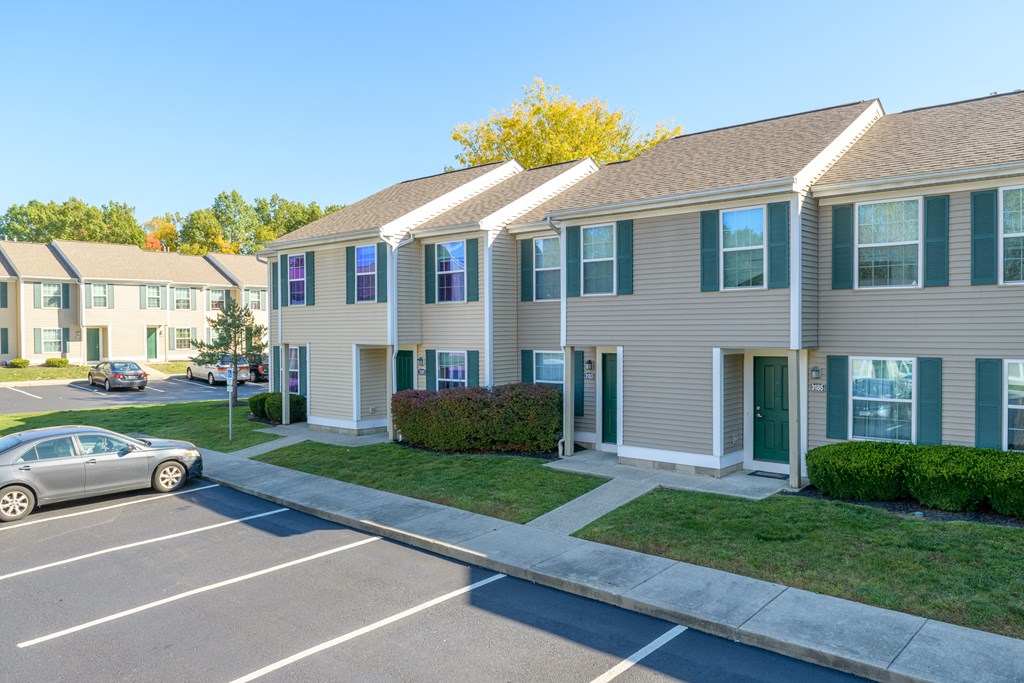 a row of apartment buildings with cars parked in a parking lot