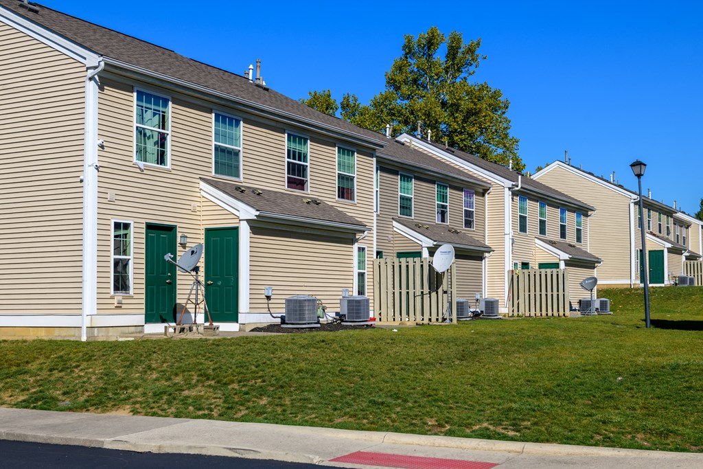a row of houses with green doors and white siding
