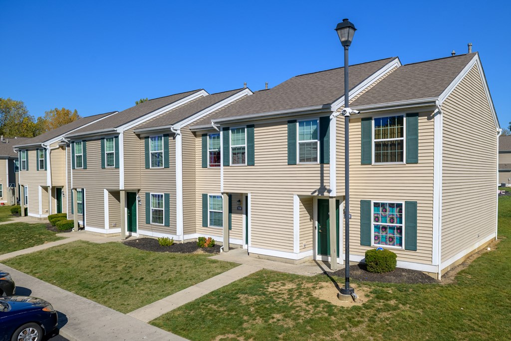 a row of townhomes with green doors and brown siding