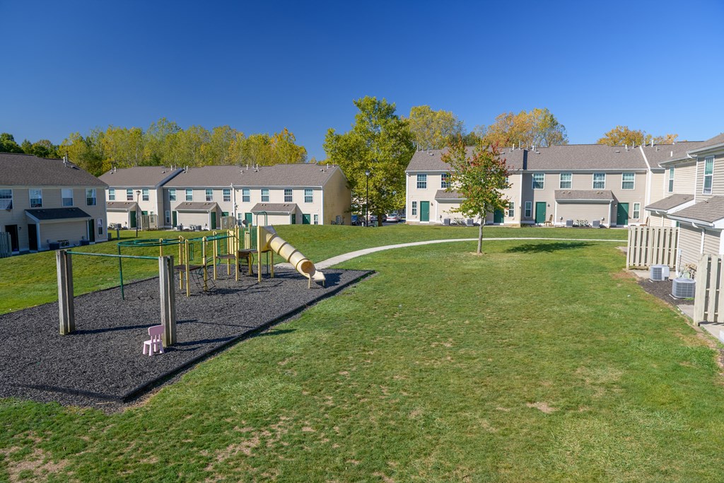 a playground in a park with houses in the background