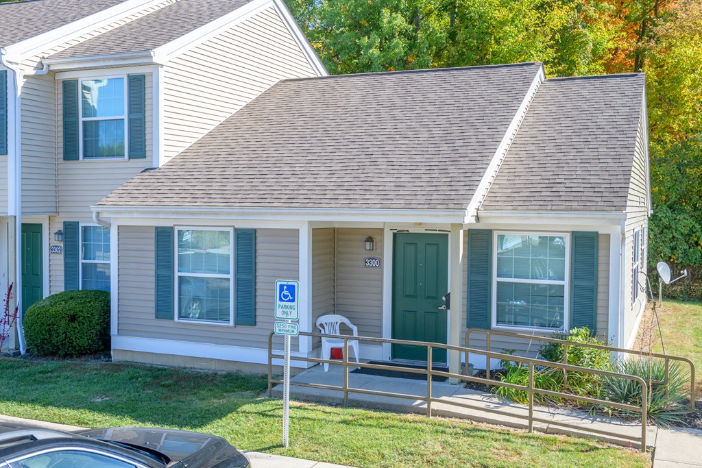 the front of a white house with a green door