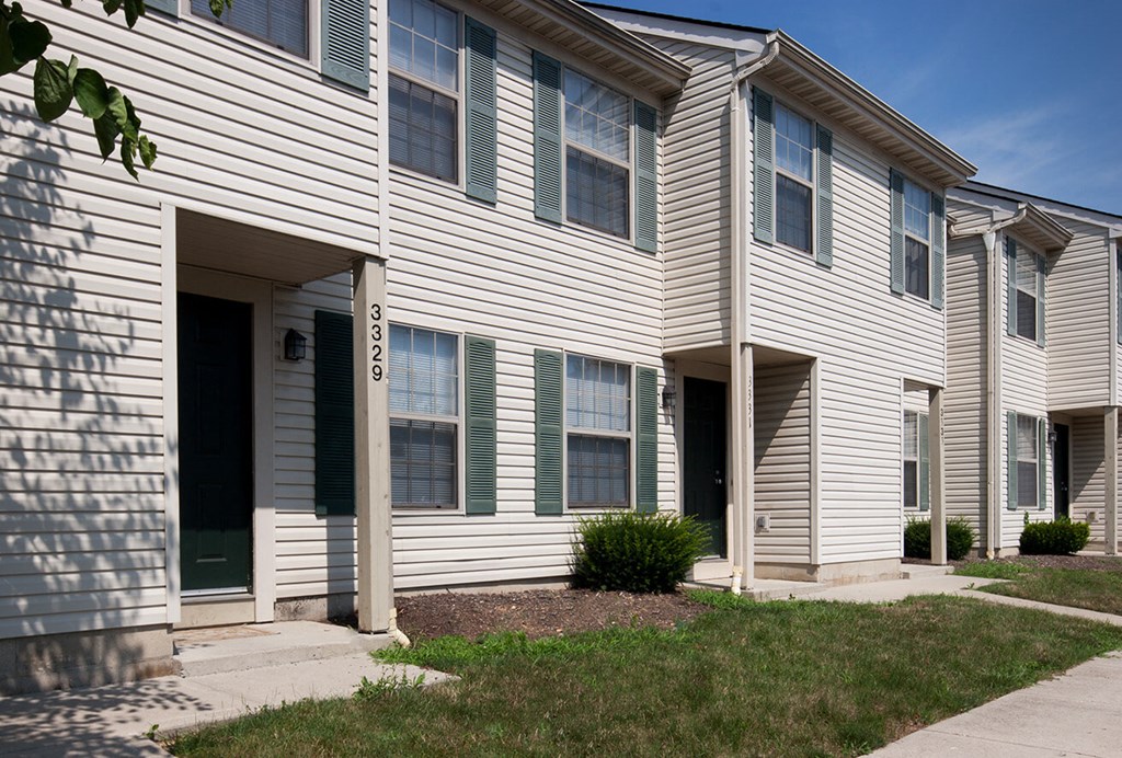 an apartment building with white siding and green shutters