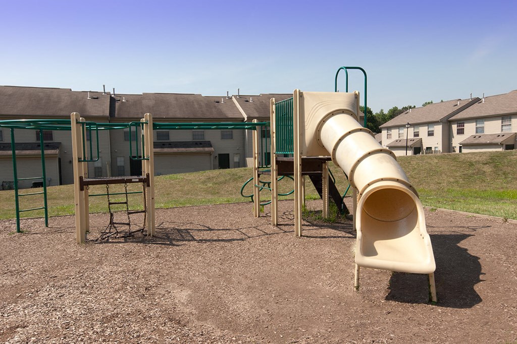 a slide at a playground with a house in the background