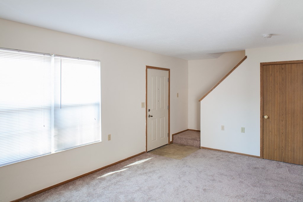 an empty living room with a large window and a door