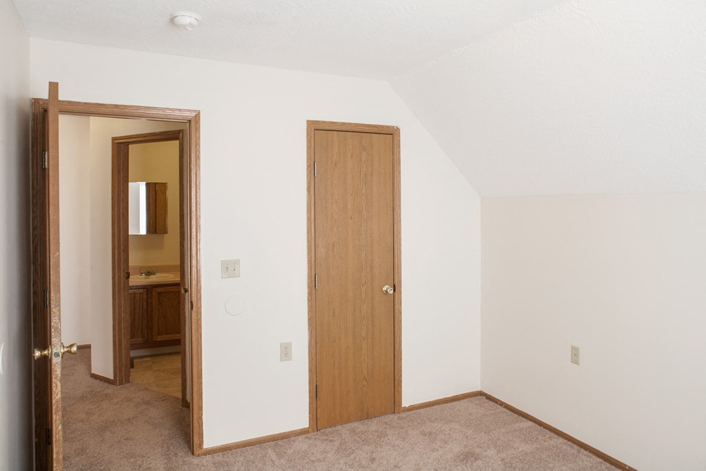 a bedroom with a door to a bathroom and a closet