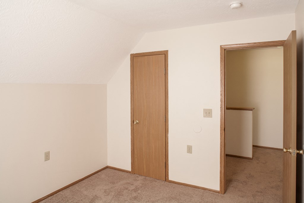an empty bedroom with a door to a closet