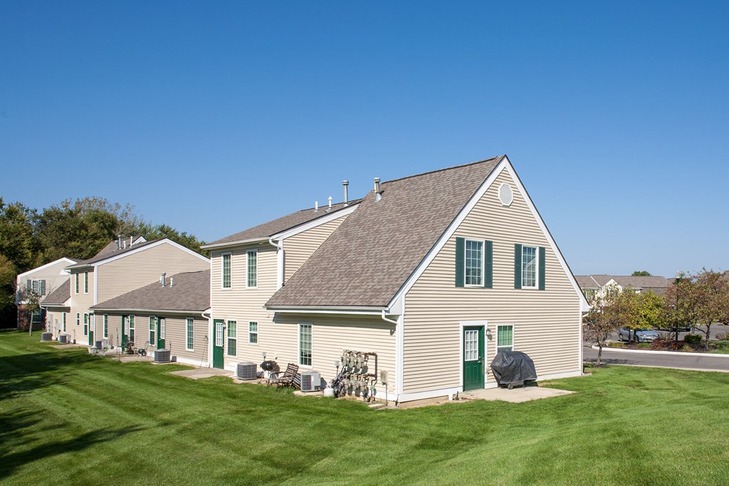 a white house with green shutters and a grassy yard