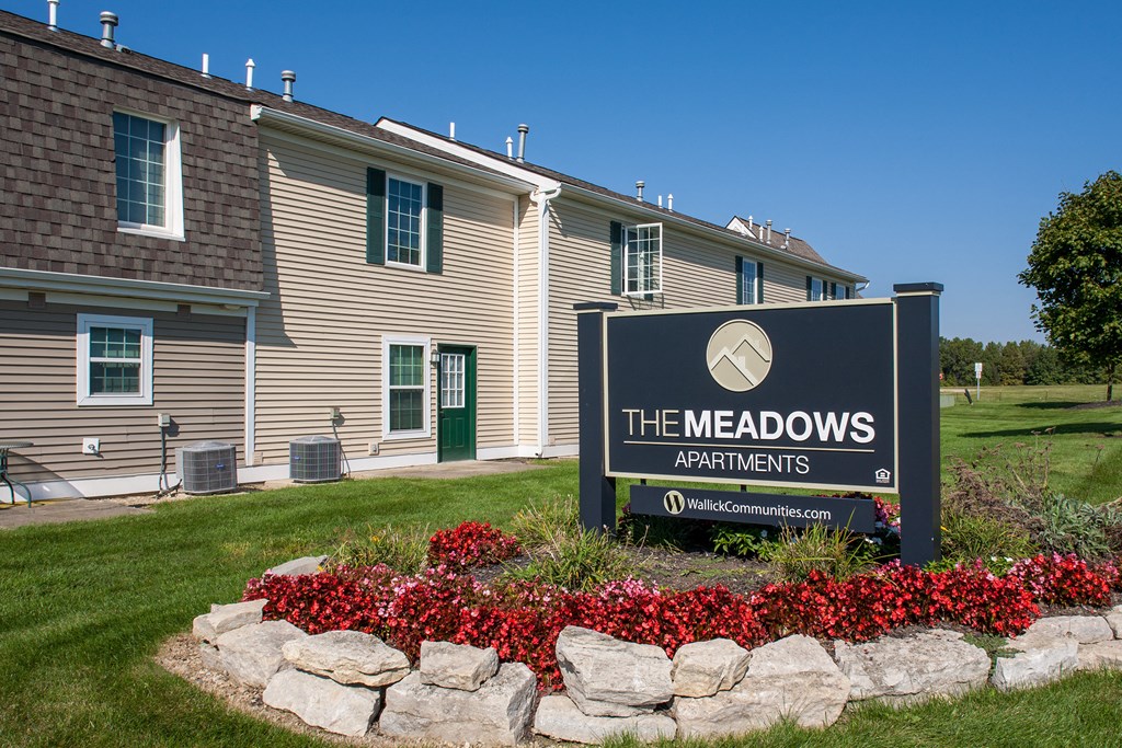 the meadows apartments sign in front of a building