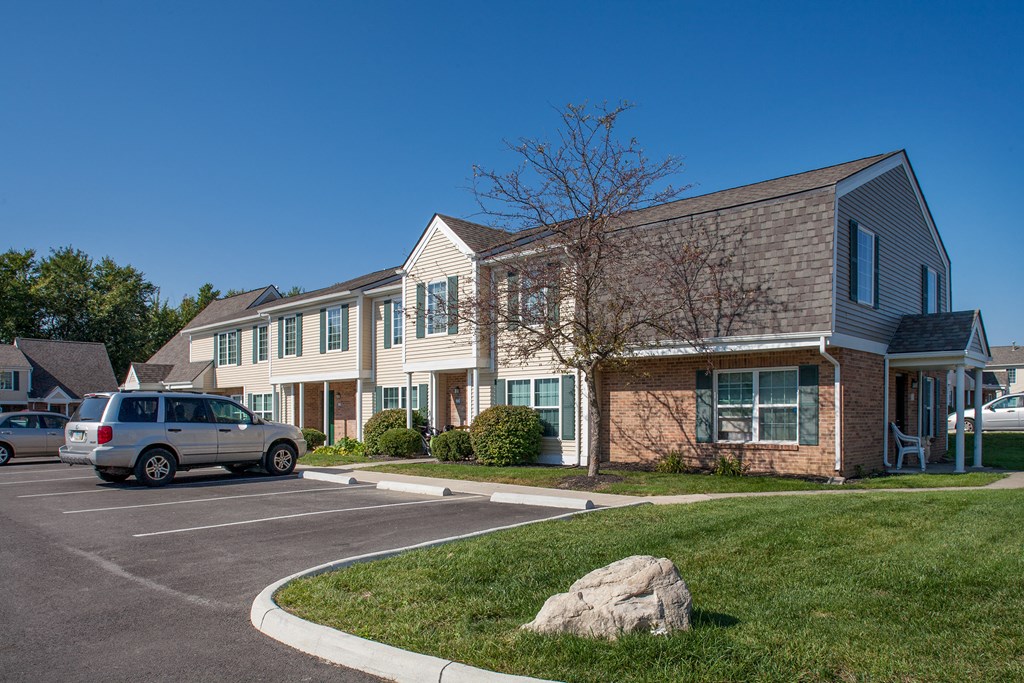 a parking lot in front of an apartment building with a van parked in the driveway