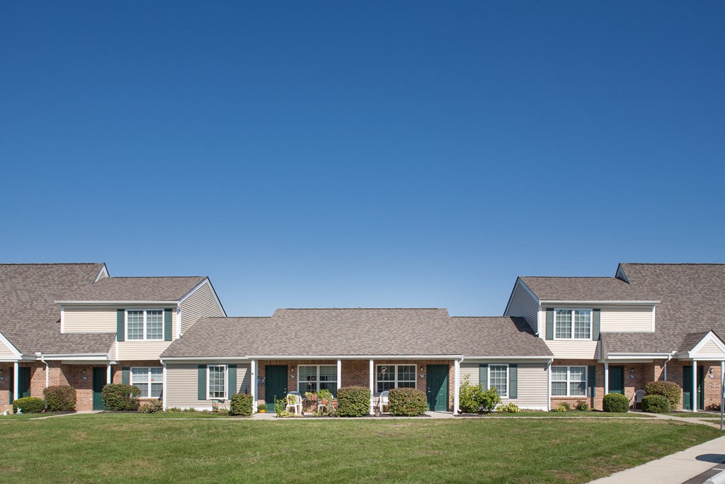 a row of houses on a lawn in front of a blue sky
