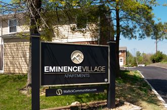 a sign for eminence village apartments in front of a house