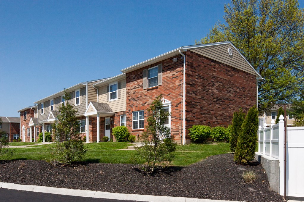 an apartment building with a red brick facade and a white fence