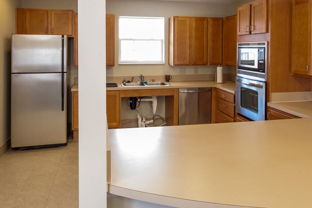 an empty kitchen with wooden cabinets and stainless steel appliances