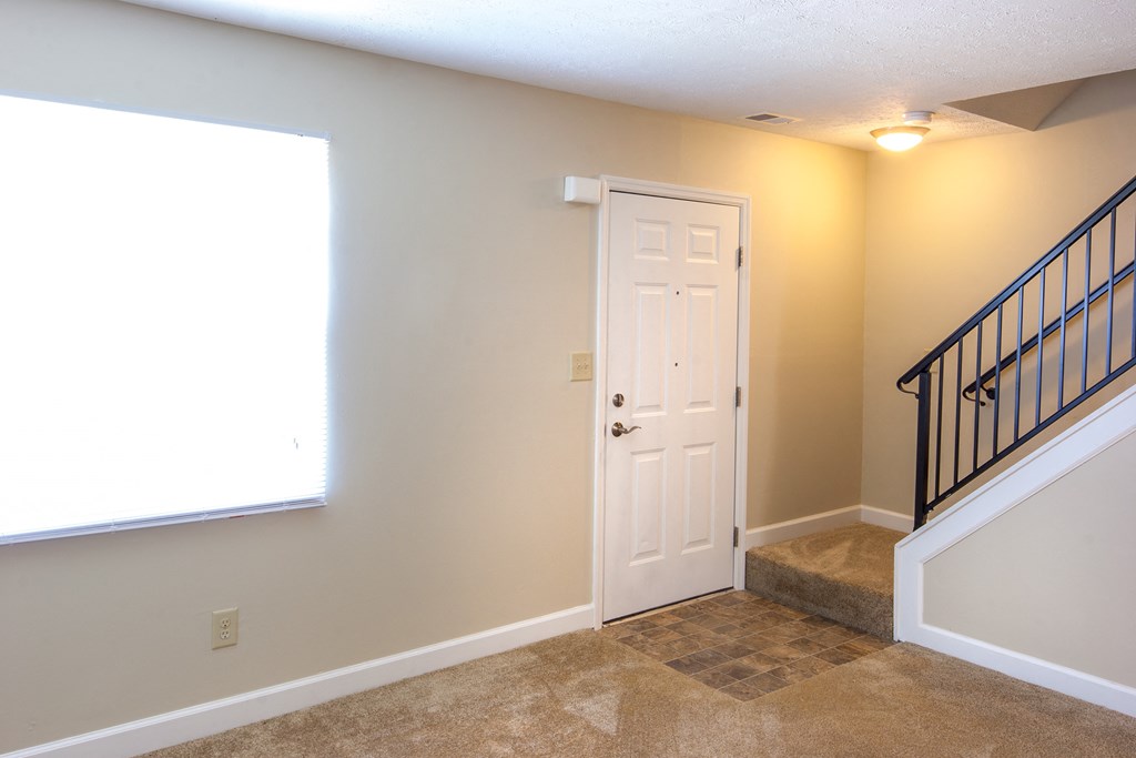 the entryway of a home with a staircase and a window and a white door