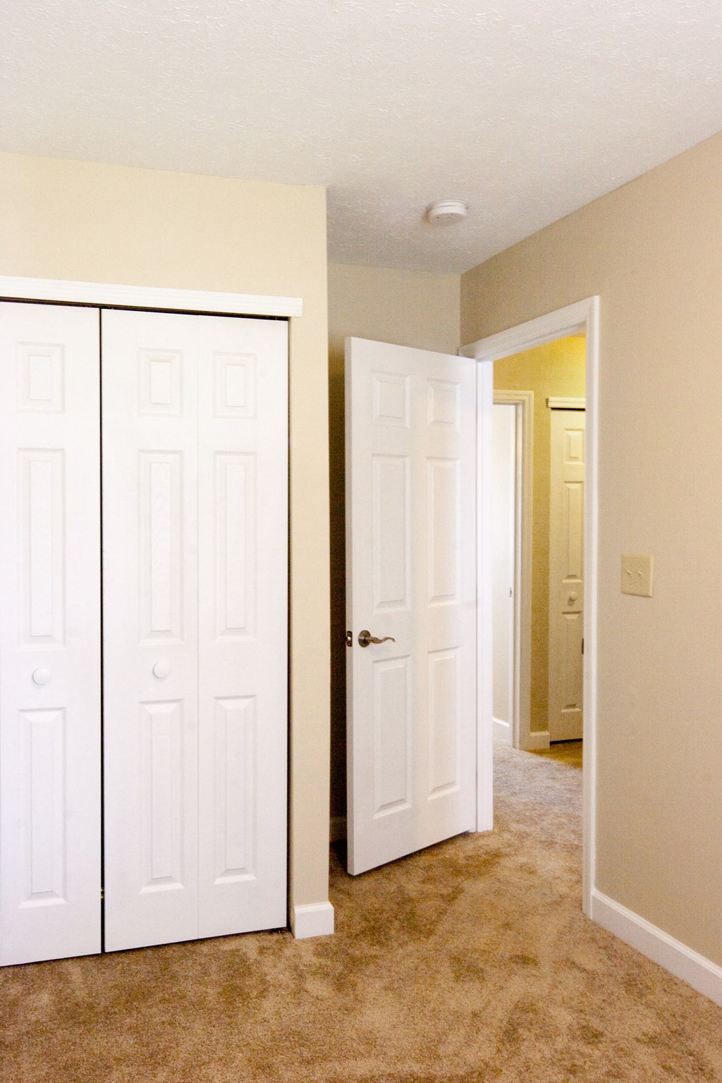 an empty room with two closet doors and a door to a hallway