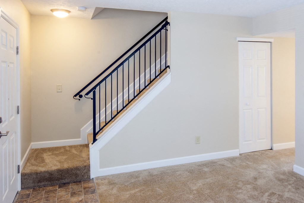 the landing of a staircase in a home with white walls and a door