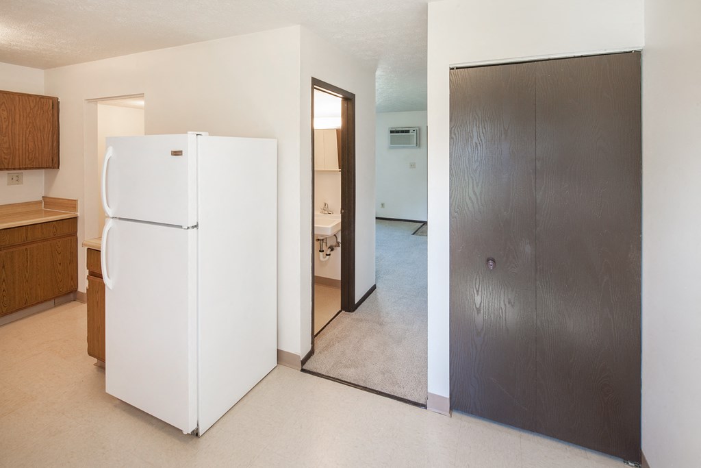 an empty kitchen with a refrigerator and a door to a bathroom