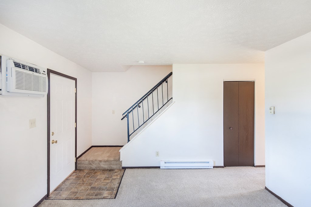 an empty living room with a staircase and a door