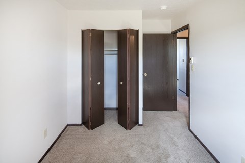 a bedroom with three closet doors and a carpeted floor