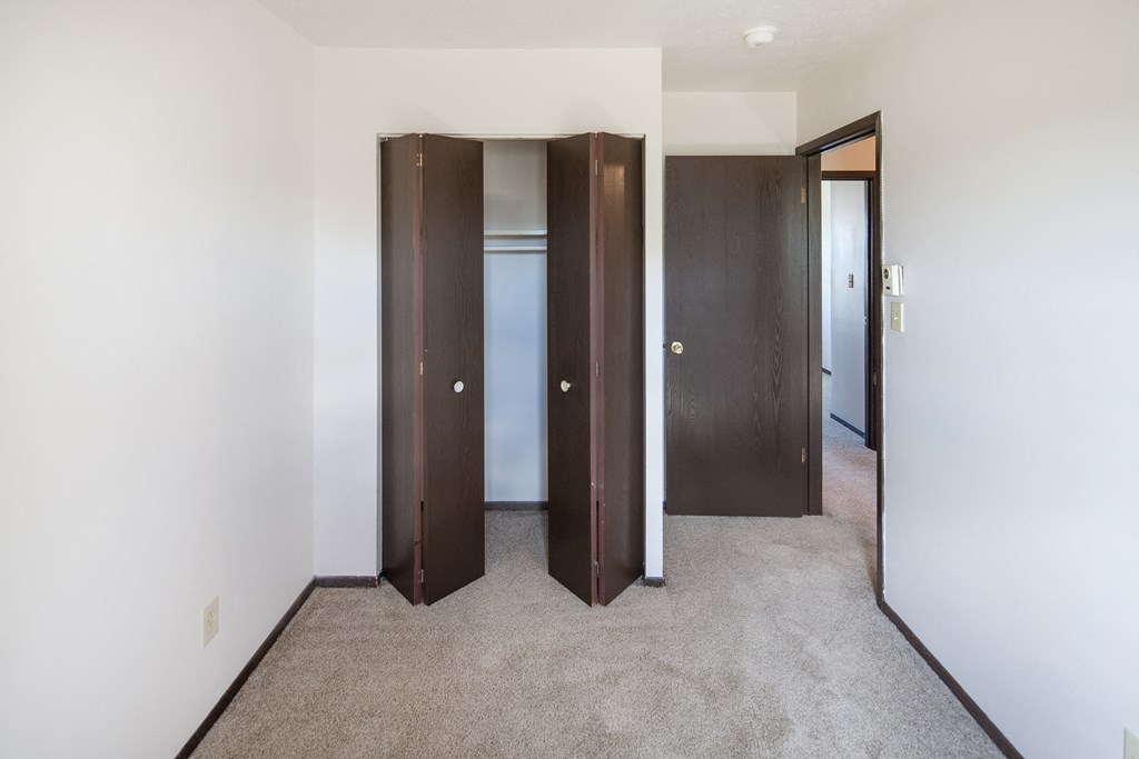 a bedroom with three closet doors and a carpeted floor