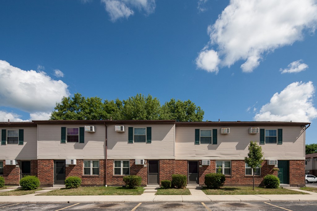 A row of townhouses with green shutters and a clear blue sky above.