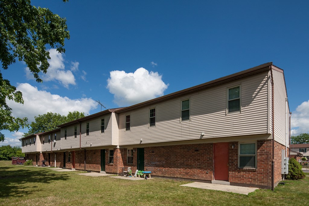 A long building with a red door sits in a grassy area.