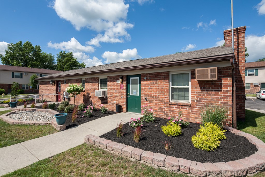 a brick house with a flower garden in front of it