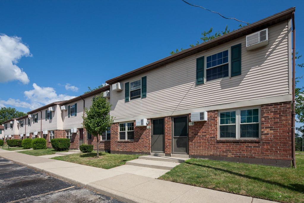 an apartment building with brick and white siding and green shutters