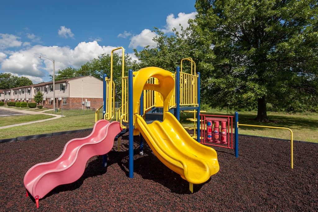 a playground with a yellow slide and a pink slide