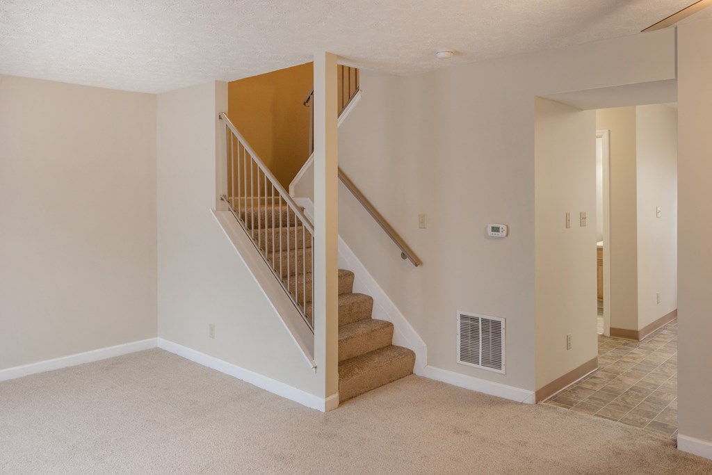 an empty living room with a staircase in a house
