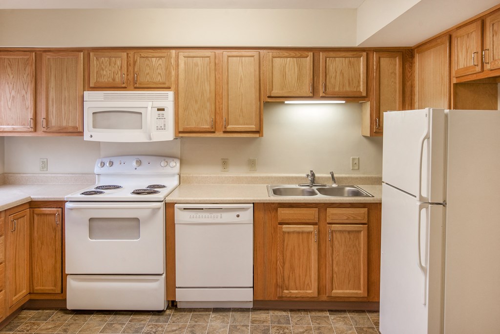 an empty kitchen with white appliances and wooden cabinets