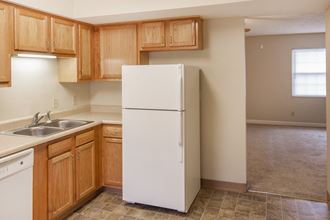 an empty kitchen with a white refrigerator and wooden cabinets