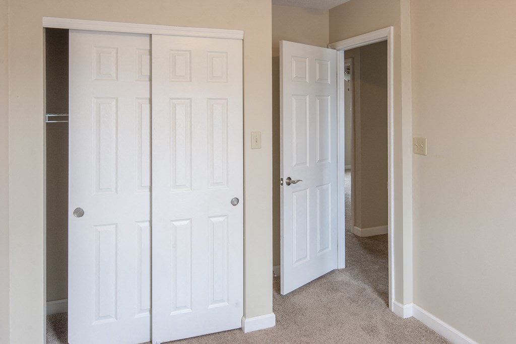 an empty bedroom with two closets and a door to a hallway