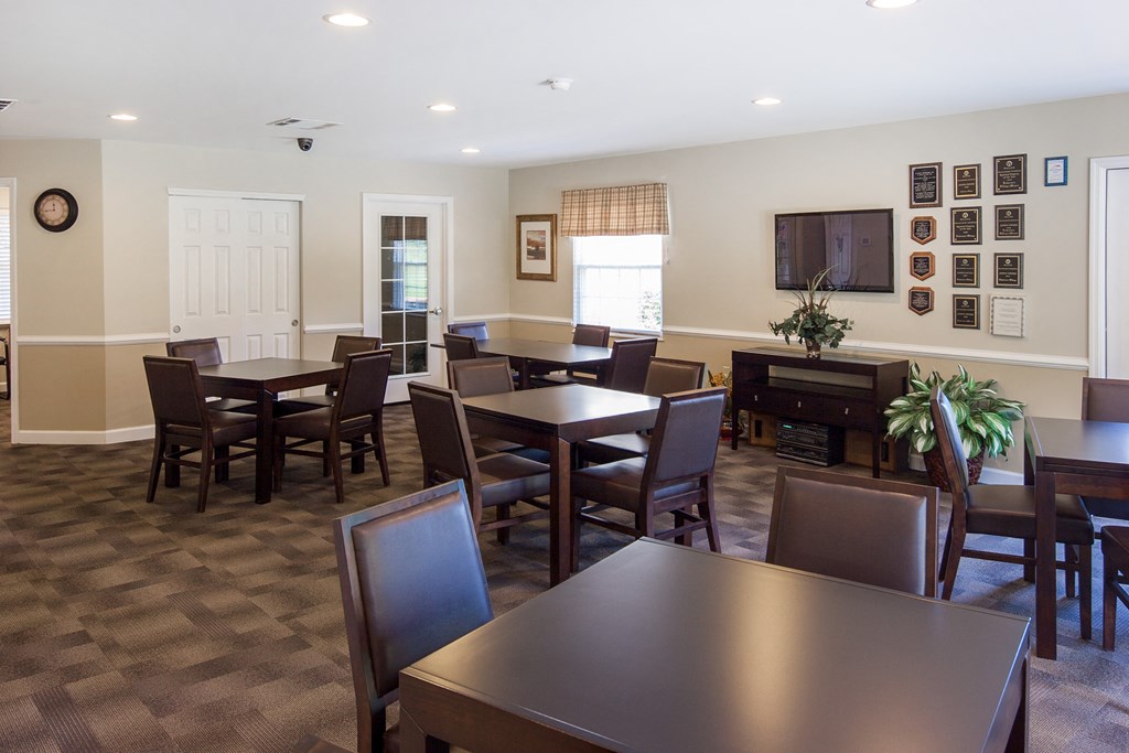 a dining room with tables and chairs and a tv in a resident clubhouse