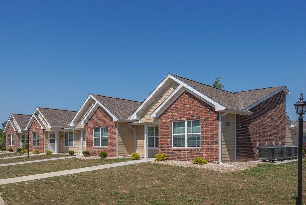 a row of brick homes with a lawn and a blue sky