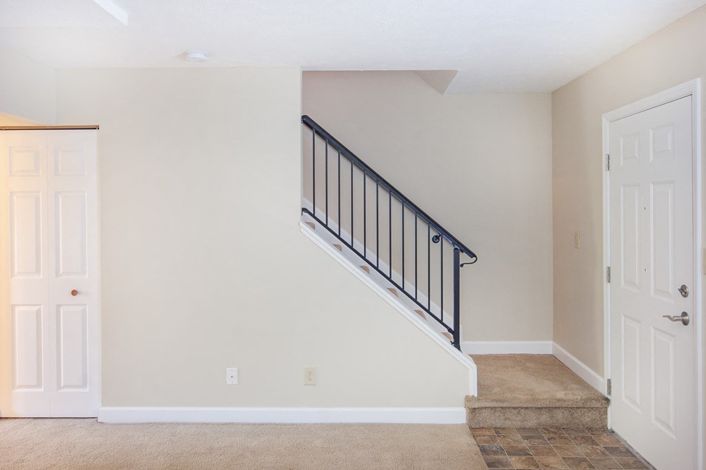 an empty living room with a staircase in a home with white doors