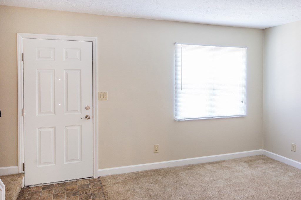 an empty room with a white door and a window