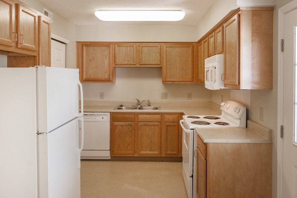 an empty kitchen with wooden cabinets and white appliances