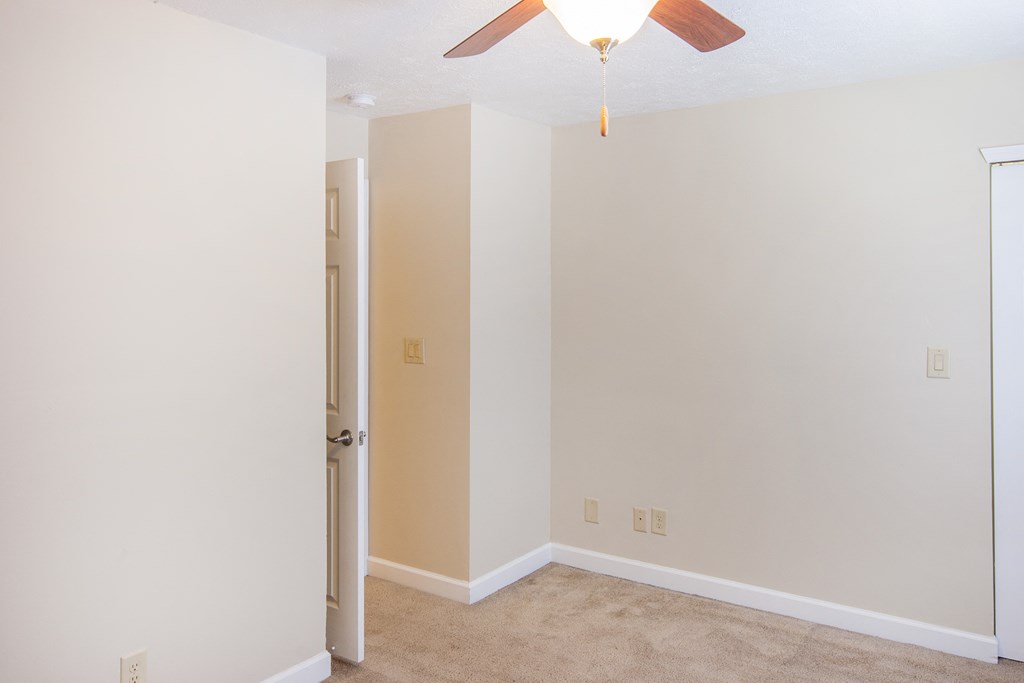 an empty room with a ceiling fan and a door