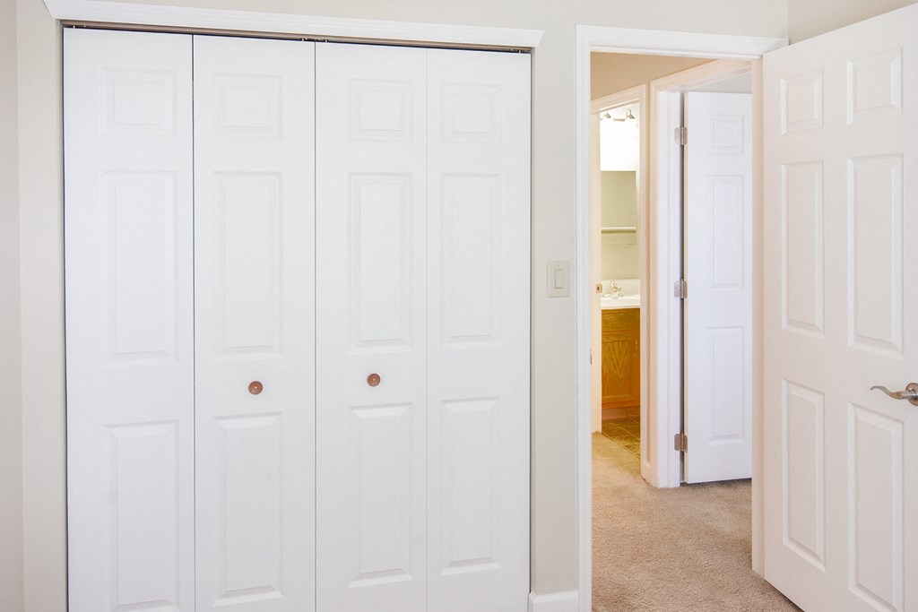 a row of closets with white doors and a bathroom in the background