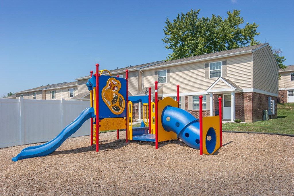 a playground with a blue and yellow play set in front of a house