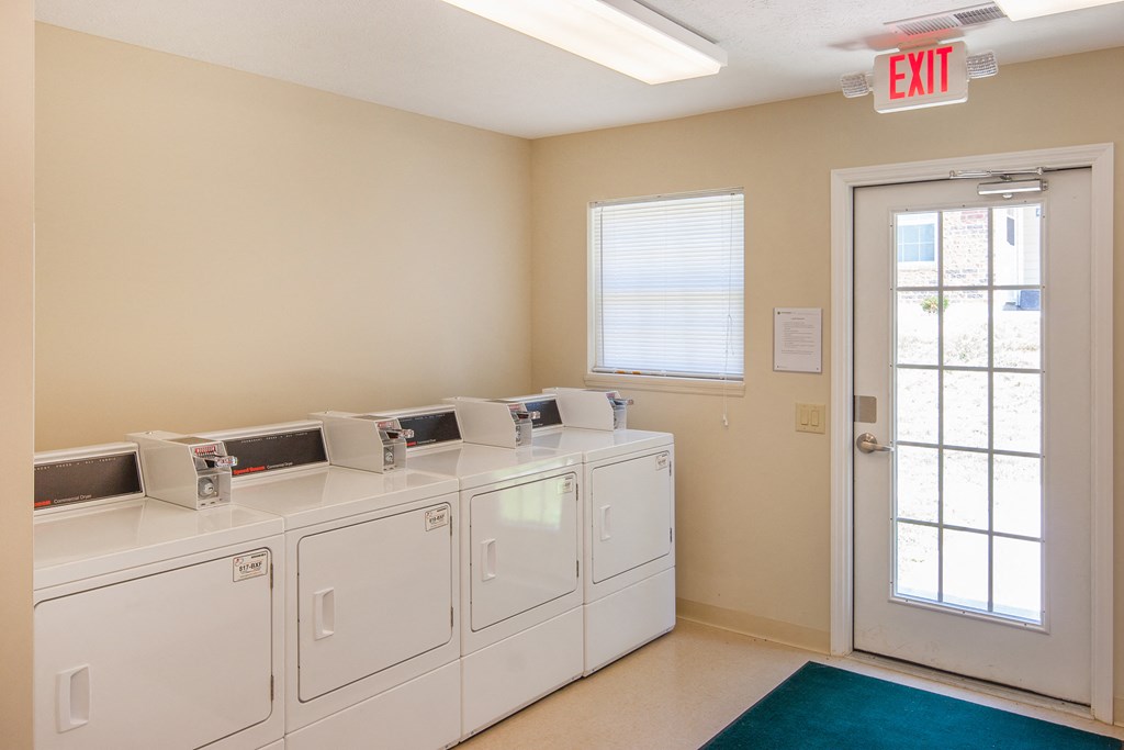 a laundry room with washers and dryers and an exit door