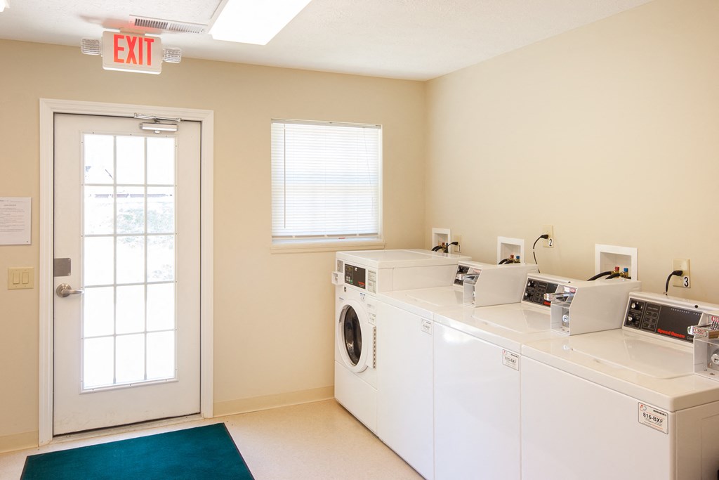 a laundry room with two washing machines and a door with an exit sign