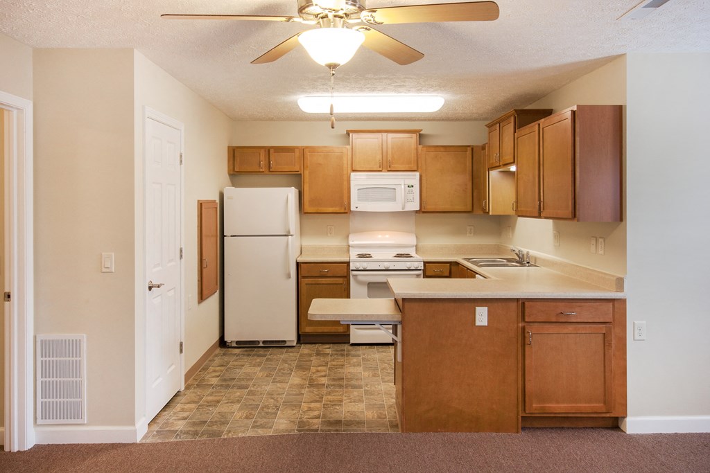 an empty kitchen with wooden cabinets and a white refrigerator