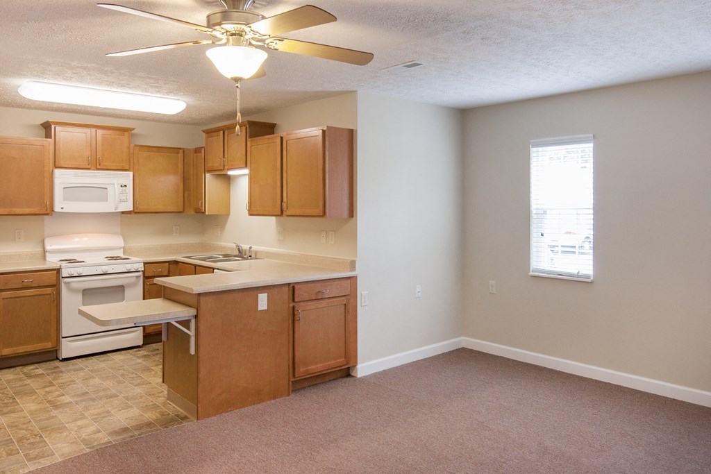 an empty kitchen with wooden cabinets and appliances and a ceiling fan