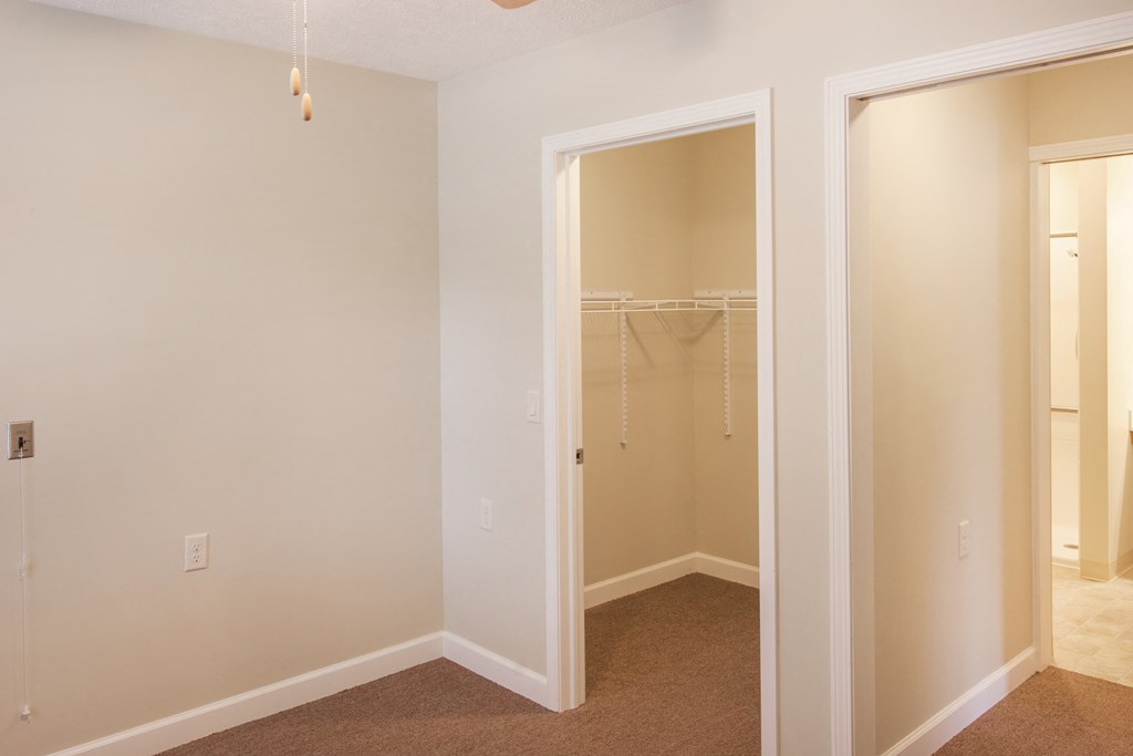 an empty bedroom with a closet and a mirrored closet door