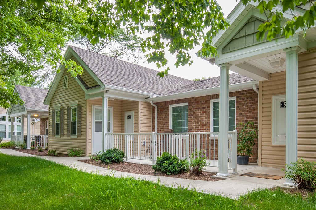 a home with a white porch and a brick house