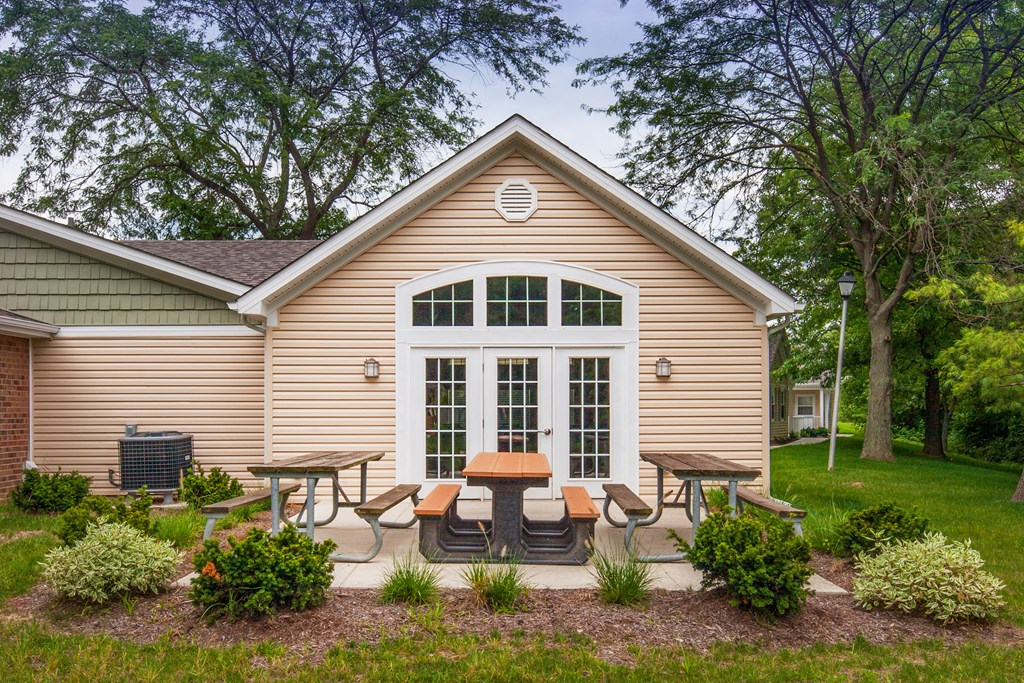 a patio with chairs and tables in front of a small house