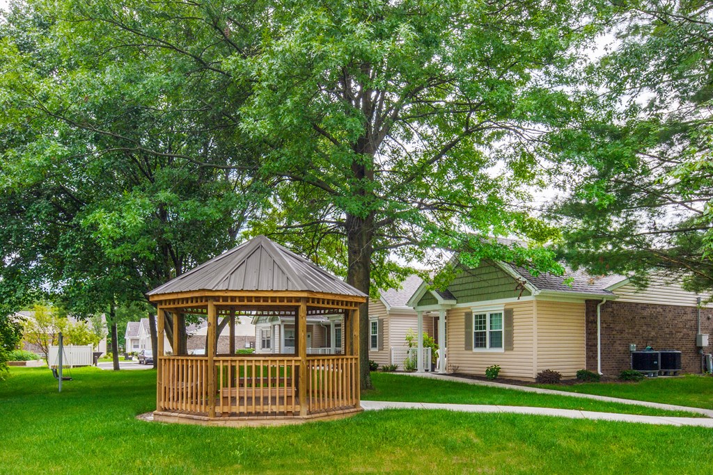 a gazebo in the middle of a yard in front of a house