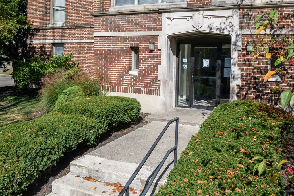 the front entrance of a brick building with stairs and a glass door